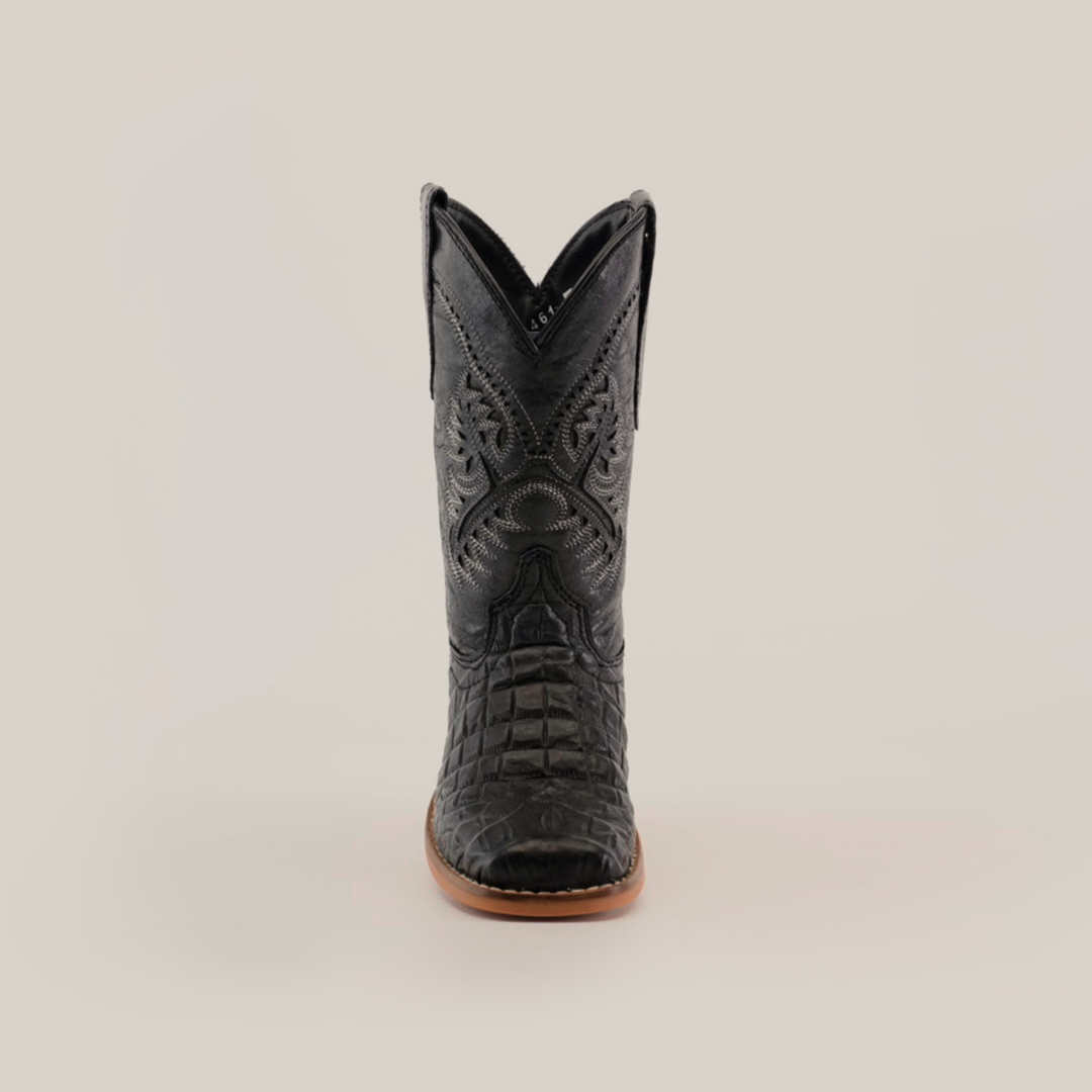 A front-facing view of a single Caiman Belly Print Black Square Toe cowboy boot exhibits an intricate black leather design, a pointed toe, and a light brown sole set against a plain white backdrop—ideal for cowboy enthusiasts.