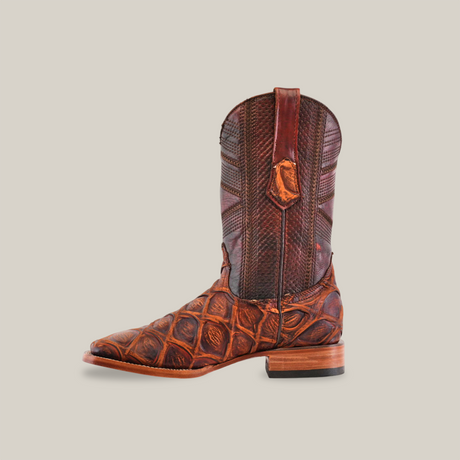 A single Big Bass Pirarucu Print Rustic Cogñac cowboy boot, featuring a textured reptile-like design, flat heel, and pull straps on the sides, is displayed against a plain white background.