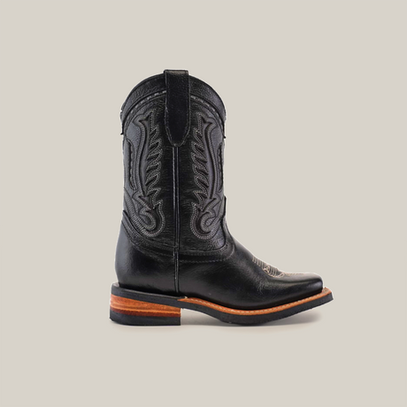 The Barcelona Black Lustre Rodeo Toe boot, made of premium cowhide leather, features shaft stitching, a wooden heel and sole, and a pull strap.