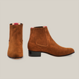 The Prime Suede Caramel Round Toe boots are handcrafted with brown suede, feature slight heels, elastic side panels, and a red plaid lining. One boot shows the back while the other displays a stylish side profile, exuding classic Western charm.