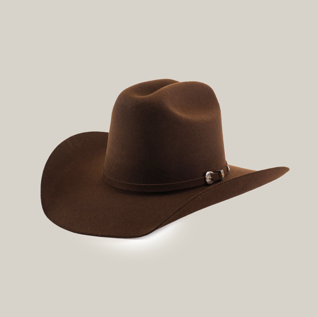 The 6X Leandro Brown is a premium cowboy hat made from genuine sheeps wool felt, featuring a wide brim and decorative band with a silver buckle. Its angled design enhances traditional aesthetics and showcases its smooth texture.