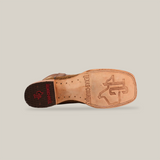 Bottom view of a single Elephant Print Orix - Square Toe boot shows a tan leather sole with the Texas Country logo. The dark heel has a small red logo. Crafted from premium leather, this handcrafted boot showcases an elegant design on a white background.