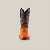 The Cater Honey Square Toe is a meticulous cowboy boot made from brown cowhide leather with a black embroidered shaft. It features intricate stitching and a rounded toe, set against a plain white background to emphasize its handcrafted quality.