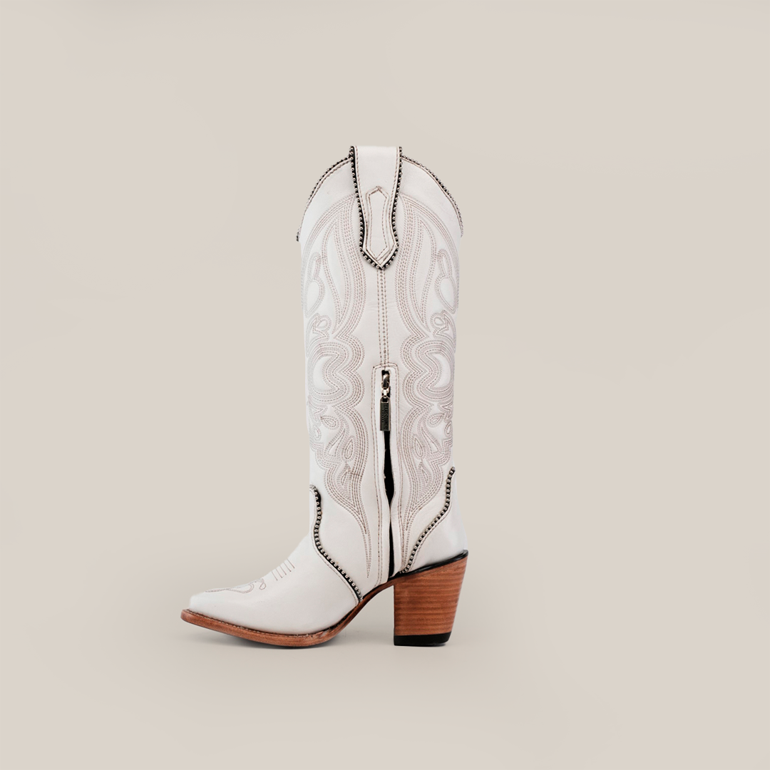 The Linda Studs Tall Shaft Frost White - J Toe boot is crafted from premium leather, featuring intricate embroidery, a pointed toe, a wooden heel, and black stitching. Part of the Platinum Collection, it stands upright against a plain light background.