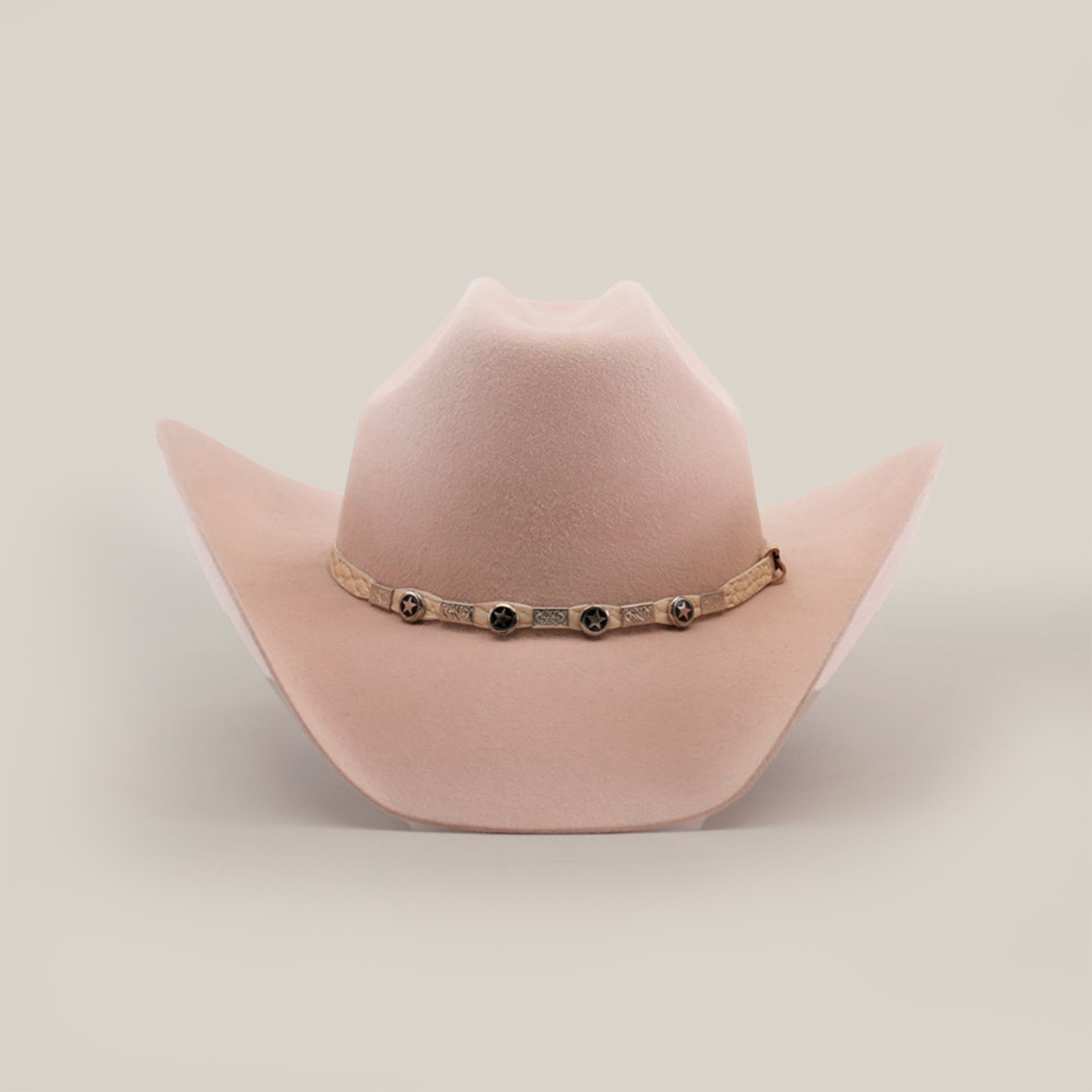 The 6X Bull Belly is a luxury western wear accessory featuring a light beige cowboy hat with a wide brim and adorned with round metal accents on the decorative band around the crowns base, all set against a plain white background.