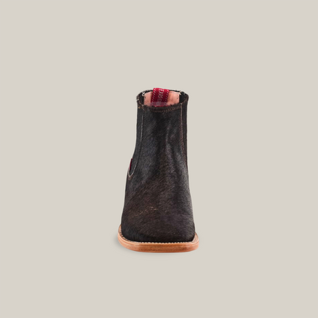 Front view of the Cowhide Hair Black Square Toe ankle boot, crafted from black cowhide leather with a brown sole, against a white background. It features a square toe and pull tab with red detailing.