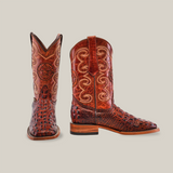 The Morelet Crocodile Print Cogñac boots, featuring a rich brown cowhide leather with ornate stitching and textured crocodile print overlays, offer a square toe and wooden heel, all set against a white background for that classic cowboy flair.